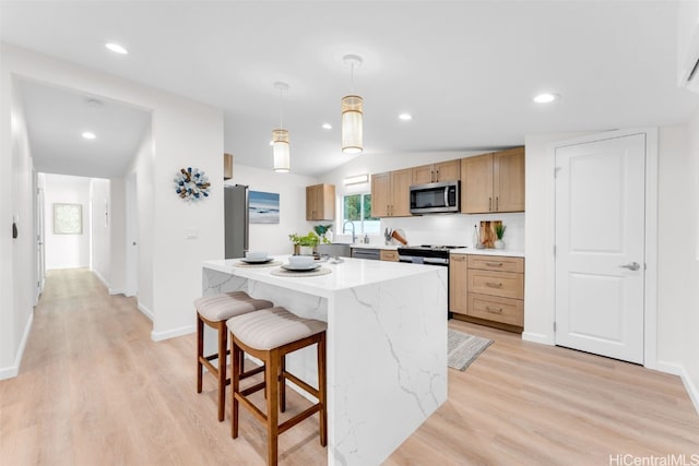 kitchen featuring a center island, stainless steel appliances, pendant lighting, lofted ceiling, and light wood-type flooring