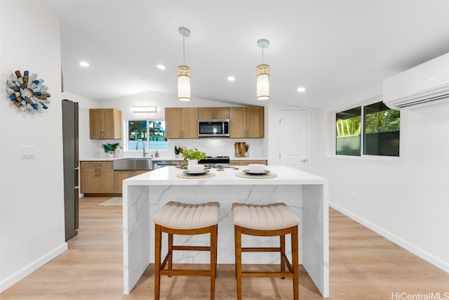 kitchen featuring appliances with stainless steel finishes, decorative light fixtures, a kitchen island, and a wealth of natural light