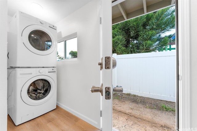 laundry area with light hardwood / wood-style floors and stacked washer / dryer