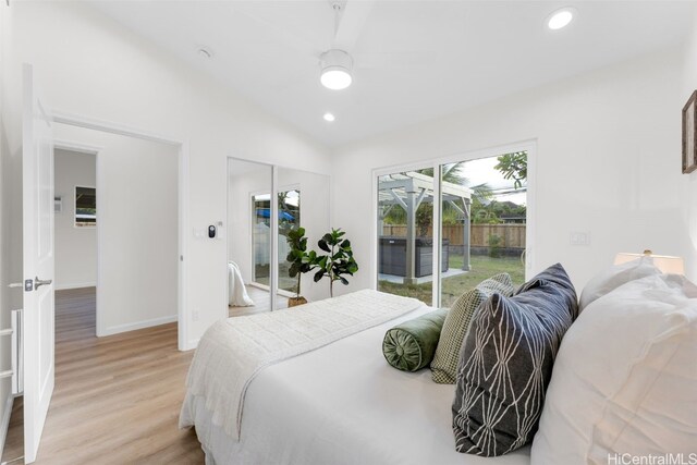 bedroom with light wood-type flooring, access to outside, and vaulted ceiling