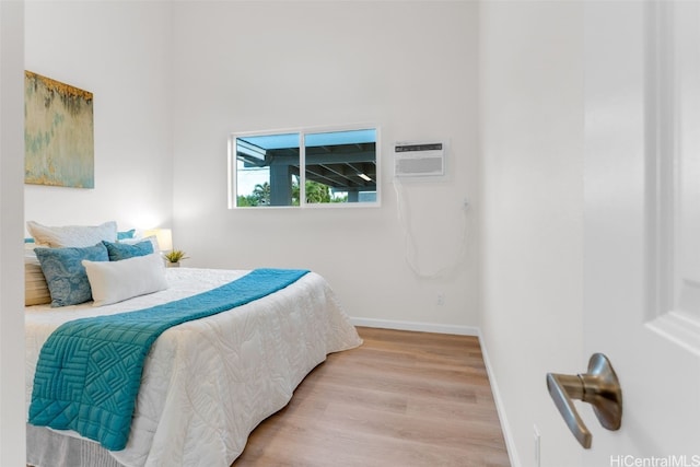 bedroom featuring a wall mounted air conditioner and hardwood / wood-style flooring