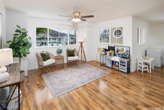 sitting room with ceiling fan, wood-type flooring, and a wealth of natural light