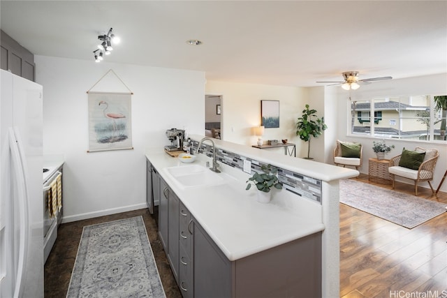 kitchen featuring white refrigerator with ice dispenser, sink, kitchen peninsula, and dark hardwood / wood-style floors