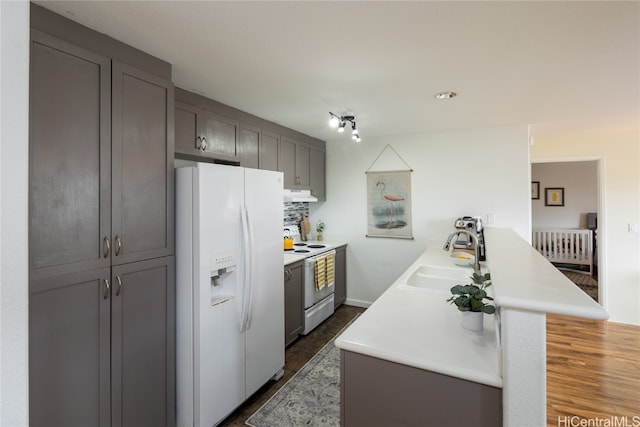 kitchen featuring gray cabinetry, sink, electric range oven, white refrigerator with ice dispenser, and dark wood-type flooring