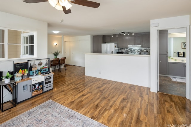 kitchen with white fridge, backsplash, dark wood-type flooring, and gray cabinets