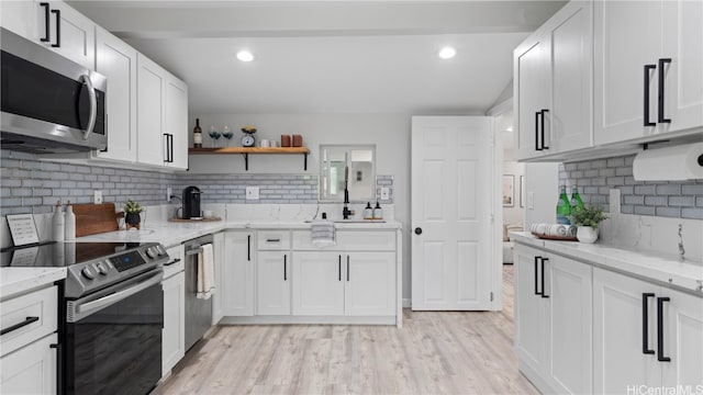 kitchen featuring appliances with stainless steel finishes, light hardwood / wood-style flooring, and white cabinetry