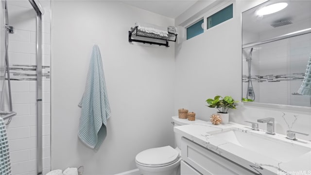 bathroom featuring toilet, vanity, and a shower with door