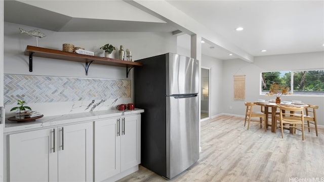 kitchen with white cabinetry, stainless steel fridge, light wood-type flooring, and backsplash