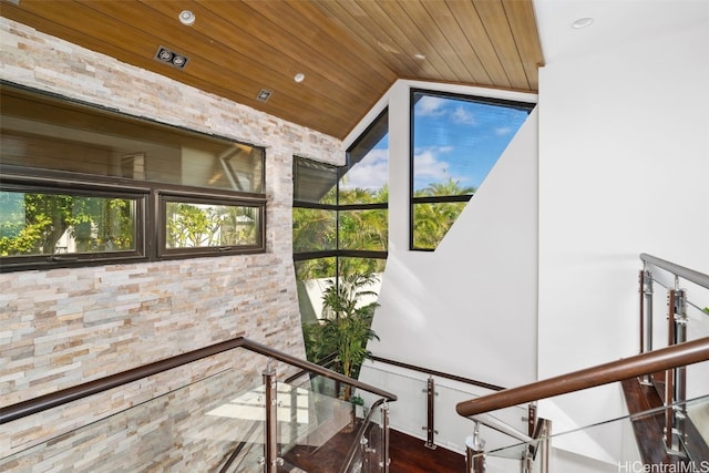 staircase with plenty of natural light, wood-type flooring, vaulted ceiling, and wood ceiling