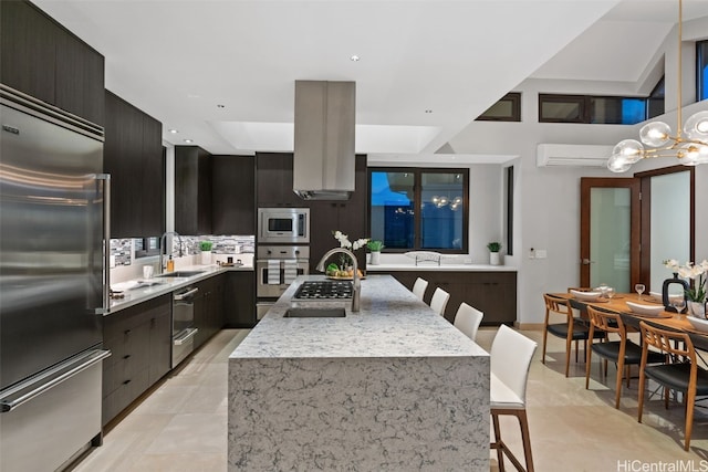 kitchen with built in appliances, decorative backsplash, sink, an island with sink, and a breakfast bar area