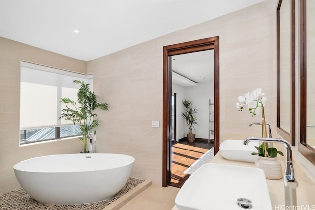 bathroom with vanity, a washtub, tile patterned floors, and tile walls