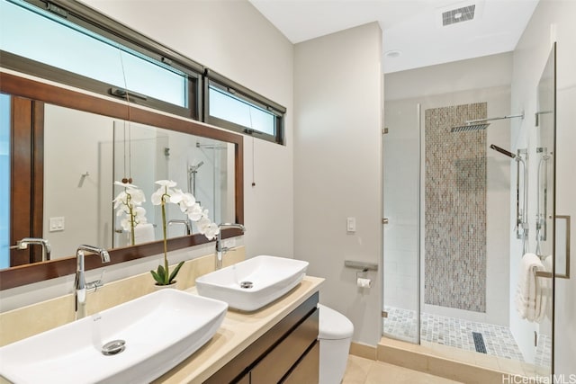 bathroom featuring toilet, vanity, tile patterned flooring, and a shower with shower door