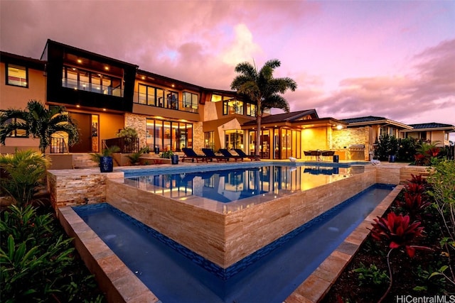 pool at dusk with a patio and a jacuzzi