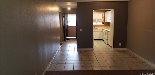 corridor with light tile patterned floors and sink