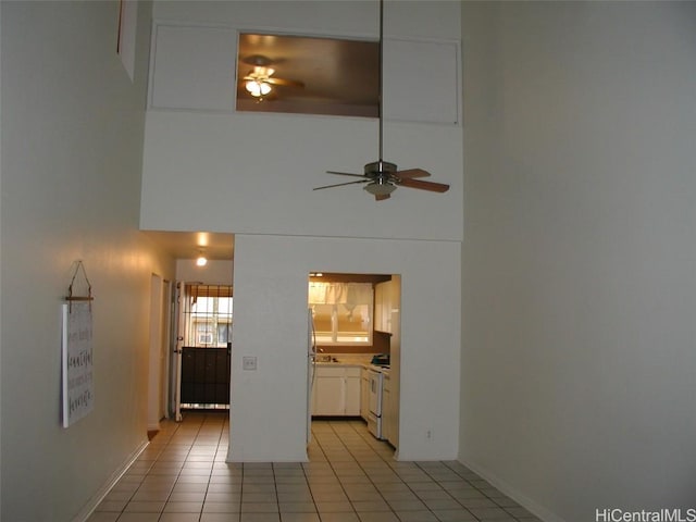 unfurnished living room with a towering ceiling and light tile patterned floors