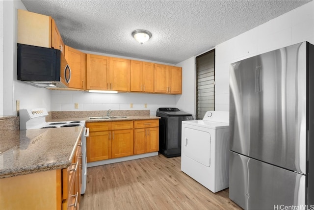 kitchen featuring washer / clothes dryer, light hardwood / wood-style flooring, stainless steel refrigerator, and stove