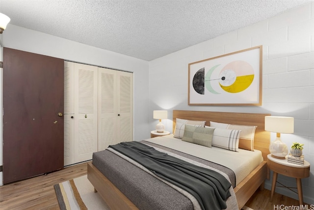 bedroom featuring a closet, a textured ceiling, and light hardwood / wood-style floors