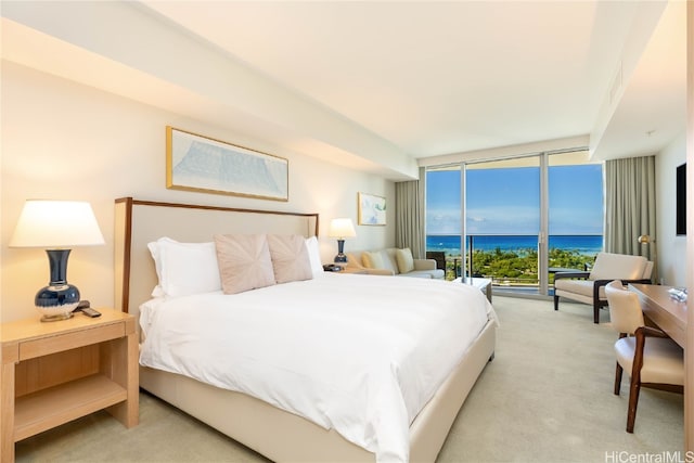 bedroom with floor to ceiling windows, light carpet, and a water view