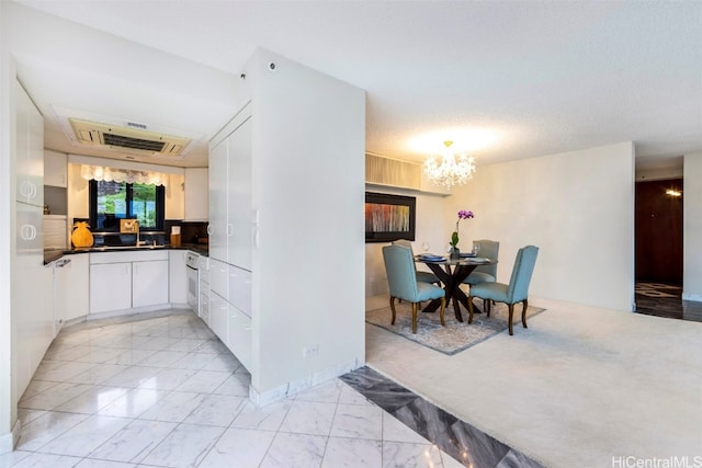 kitchen featuring a notable chandelier, white cabinets, and a textured ceiling