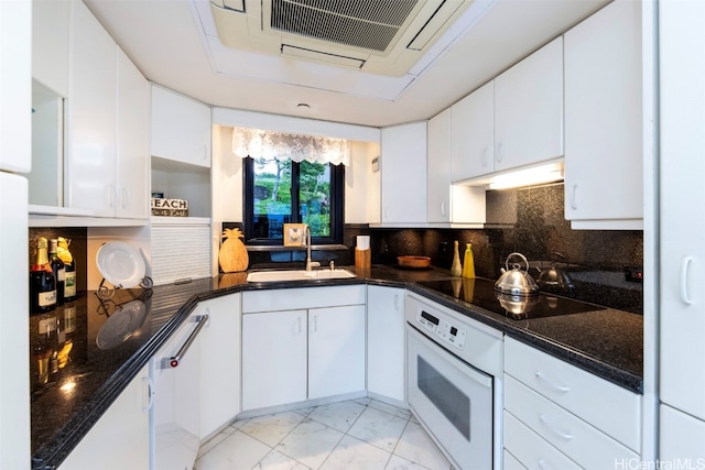 kitchen featuring white appliances, tasteful backsplash, sink, white cabinets, and dark stone countertops