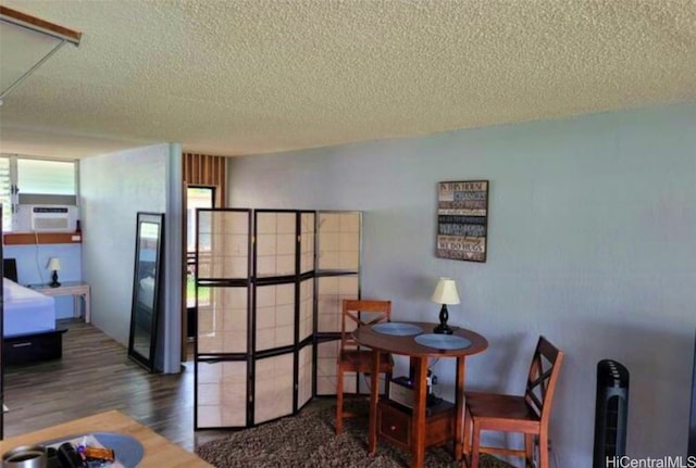 dining room featuring a wall unit AC, a textured ceiling, and dark hardwood / wood-style flooring