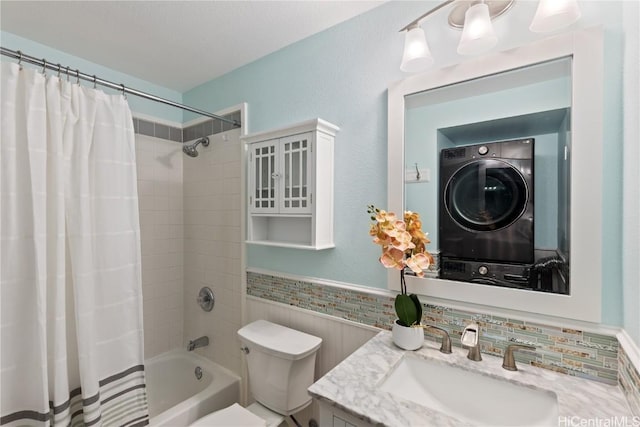 full bathroom featuring shower / bath combination with curtain, vanity, stacked washing maching and dryer, and toilet