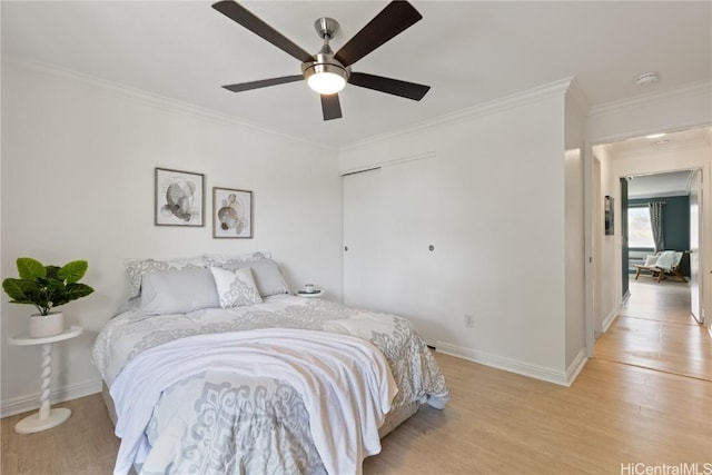 bedroom with crown molding, ceiling fan, a closet, and light wood-type flooring