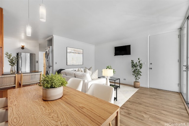 dining room featuring stacked washer / dryer and light hardwood / wood-style floors