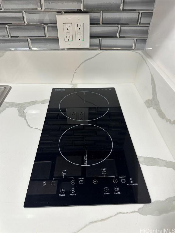 interior details with black electric stovetop and light stone counters