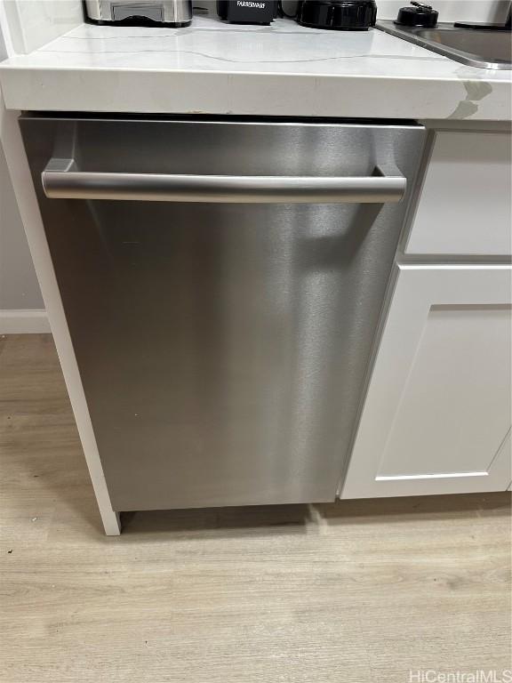 details with light stone countertops, white cabinetry, light hardwood / wood-style floors, and stainless steel dishwasher