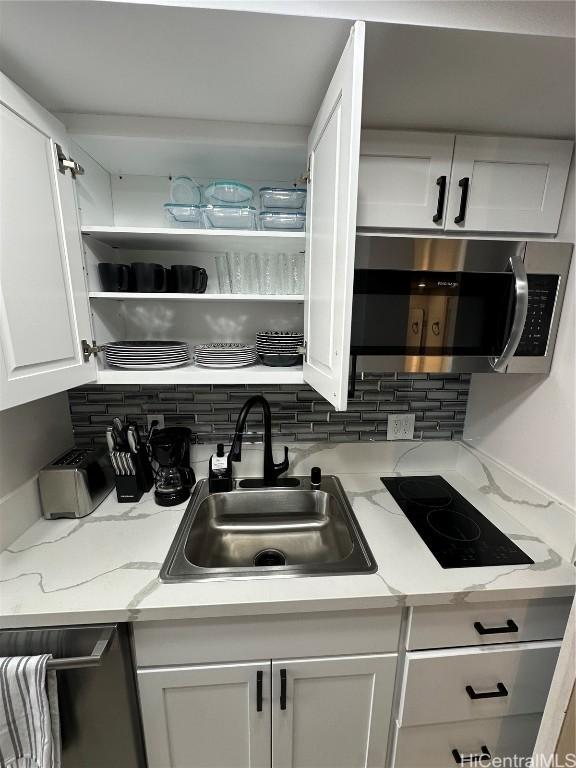 kitchen with backsplash, white cabinetry, sink, and stainless steel appliances