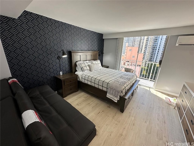 bedroom featuring light hardwood / wood-style floors, access to exterior, and a wall unit AC