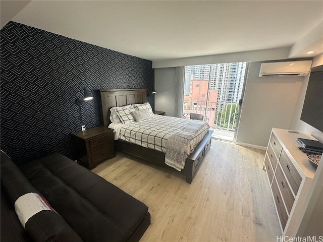 bedroom with access to exterior, light hardwood / wood-style flooring, and a wall mounted AC