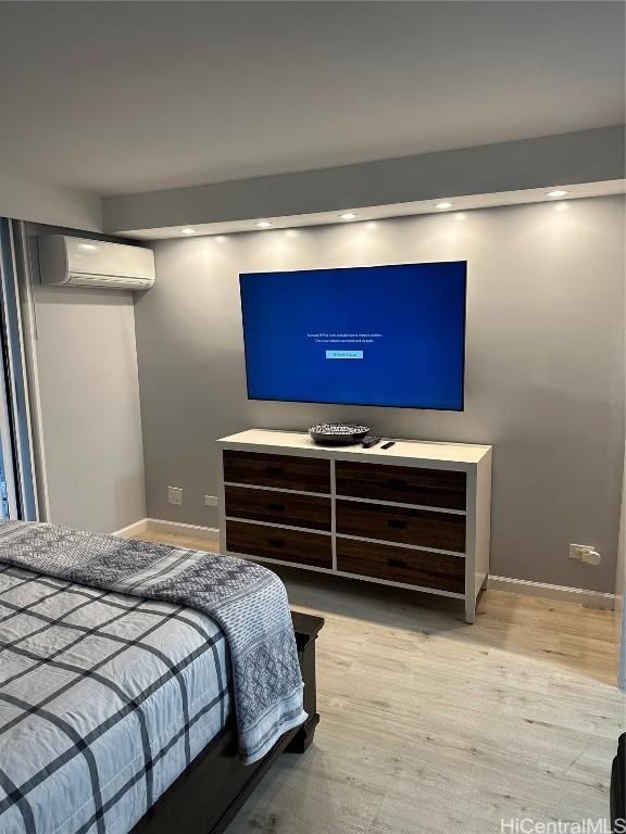 bedroom featuring a wall mounted air conditioner and light hardwood / wood-style floors