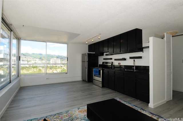 kitchen featuring a textured ceiling, sink, light hardwood / wood-style flooring, and appliances with stainless steel finishes