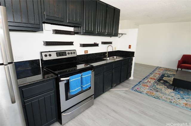 kitchen with light hardwood / wood-style floors, a textured ceiling, sink, stainless steel electric range oven, and fridge