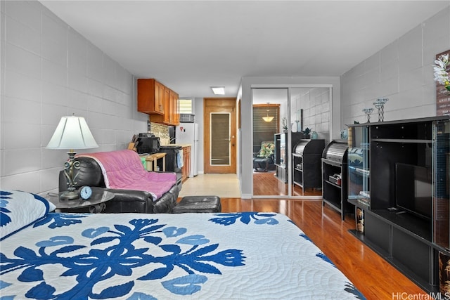 bedroom with a closet, white fridge, and light hardwood / wood-style flooring