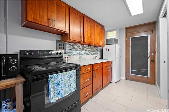 kitchen with sink, light stone counters, tasteful backsplash, black range with electric cooktop, and white fridge