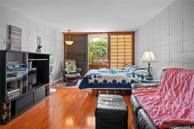 bedroom with access to exterior, expansive windows, and wood-type flooring