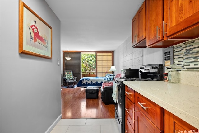 kitchen with tasteful backsplash, light wood-type flooring, and black / electric stove