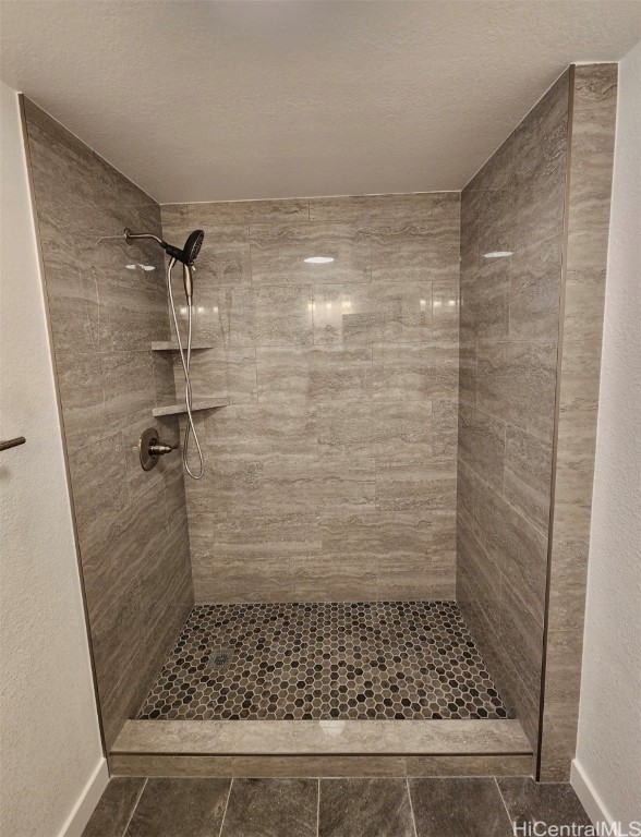 bathroom with a tile shower and a textured ceiling