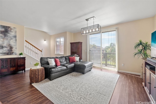 living room with stairway, dark wood-style flooring, and baseboards