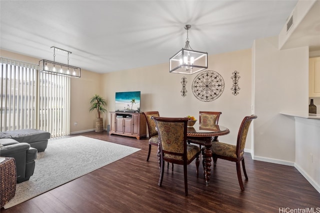 dining space featuring dark wood-style flooring, an inviting chandelier, visible vents, and baseboards