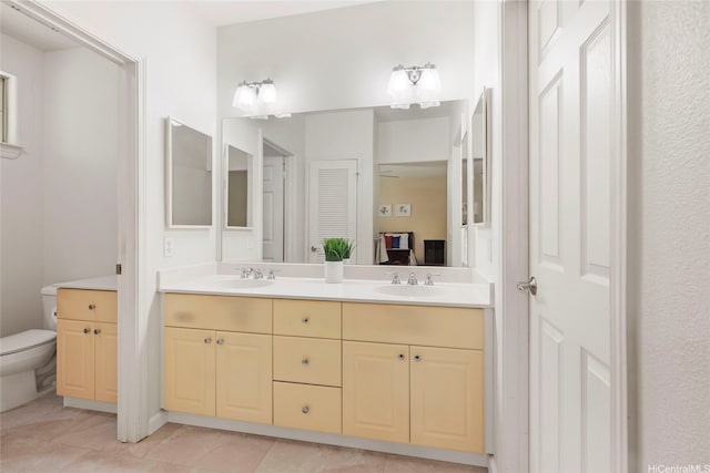 bathroom featuring tile patterned flooring, a sink, double vanity, and toilet