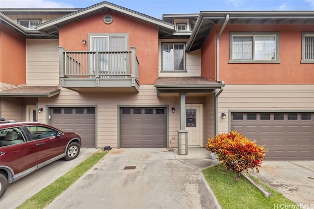 view of property featuring driveway, a balcony, an attached garage, and stucco siding