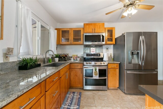 kitchen featuring sink, ceiling fan, light stone countertops, light tile patterned floors, and stainless steel appliances