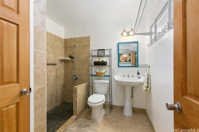 bathroom with a tile shower, tile patterned floors, sink, and toilet