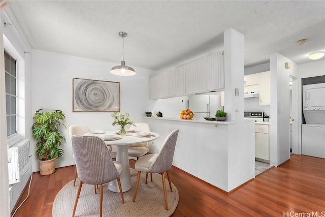 dining area with dark wood-type flooring and stacked washer / dryer