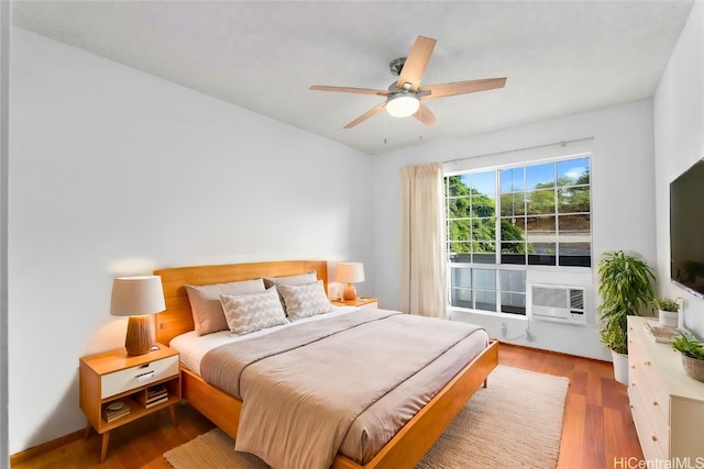 bedroom with cooling unit, hardwood / wood-style flooring, and ceiling fan