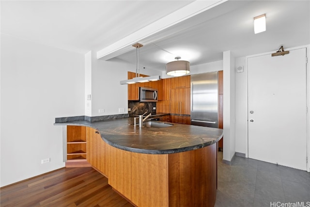 kitchen with kitchen peninsula, backsplash, appliances with stainless steel finishes, dark wood-type flooring, and sink